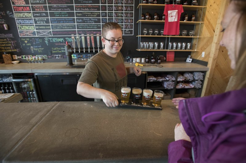 Taptender Hannah Gilliam serves a sample flight of beers to a customer Sunday at New Province Brewing Co. in Rogers. A report from earlier this year ranked Northwest Arkansas 180th out of the 200 best metropolitan areas for small business.