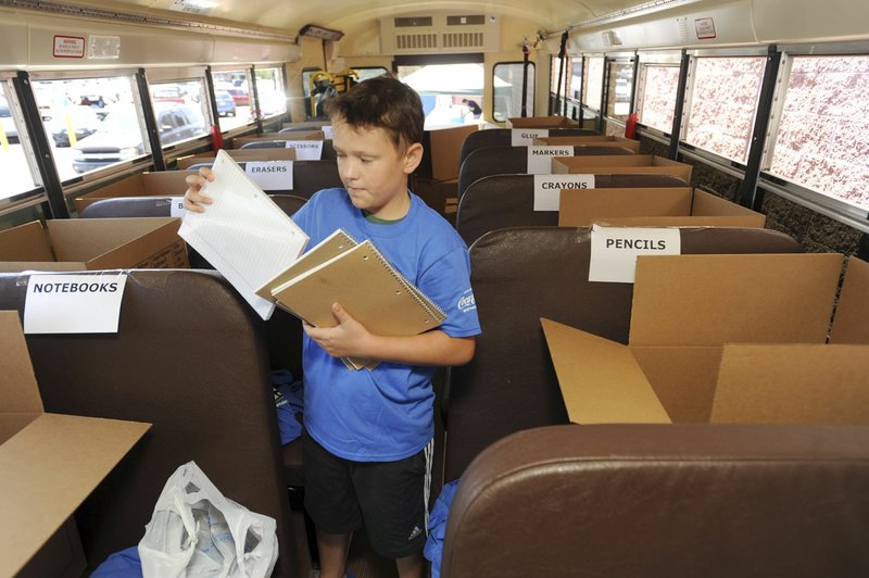 Volunteer Robin Earles, 12, of Fayetteville, a seventh-grader at Woodland Junior High School, sorts donated school supplies Friday, Aug. 4, 2017, aboard a Fayetteville School District bus at the Walmart Supercenter on Mall Avenue in Fayetteville. The United Way of Northwest Arkansas is collecting school supplies at area Walmart locations from 8 a.m. to 5 p.m. today in its annual Fill the Bus effort to benefit local school districts.