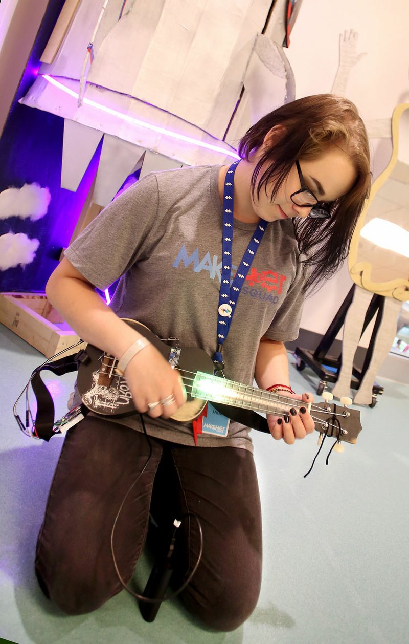 Jade Hourigan of Bentonville High School displays Monday a light-up ukulele during a celebration for students who participated in the MakeHER Squad programs at the Amazeum in Bentonville. The squad participated in in-depth learning and production in science, technology, engineering and math fields. Each participant created a unique project during the summer program.