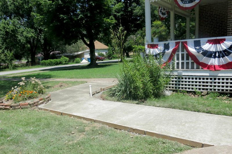 Photo by Susan Holland A new sidewalk was poured July 20 around the northwest corner of the Gravette Historical Museum. This section of sidewalk and other short sections replacing older walks behind the museum have made the grounds more easily accessible by museum patrons. The upgrades were all part of Eagle Scout projects by members of Boy Scout Troop 525 of Bentonville.