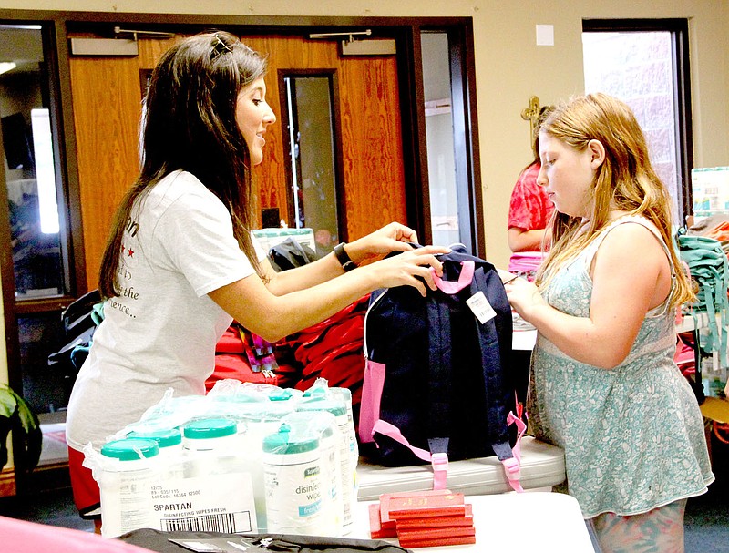 LYNN KUTTER ENTERPRISE-LEADER Rachel Lawrence, school counselor for Ledbetter Intermediate in Farmington, helps Tina Atkinson, 10, of West Fork find a new backpack. Tina attends school in Prairie Grove. See more photos on Page 7A.
