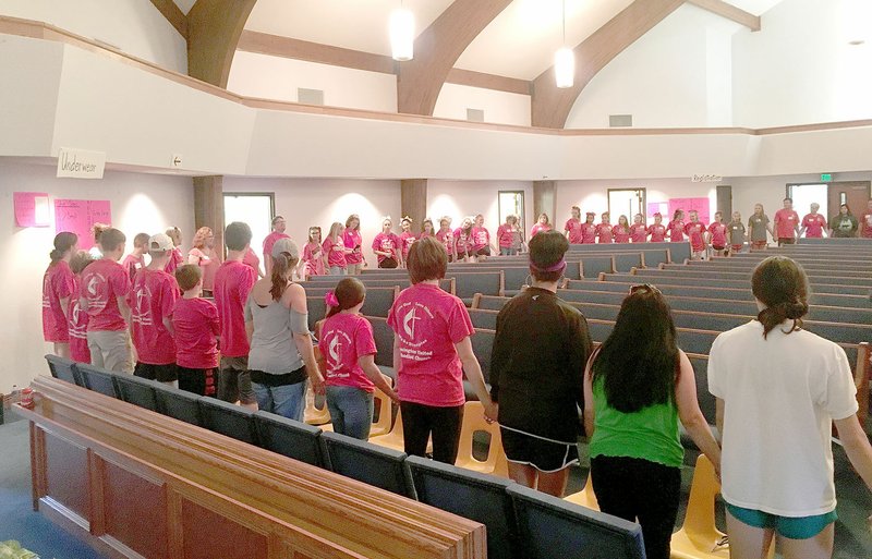 Volunteers with the Farmington Back to School Bonanza join hands in a large circle to pray before the first families come into the church. About 200 people helped with the Bonanza this year.