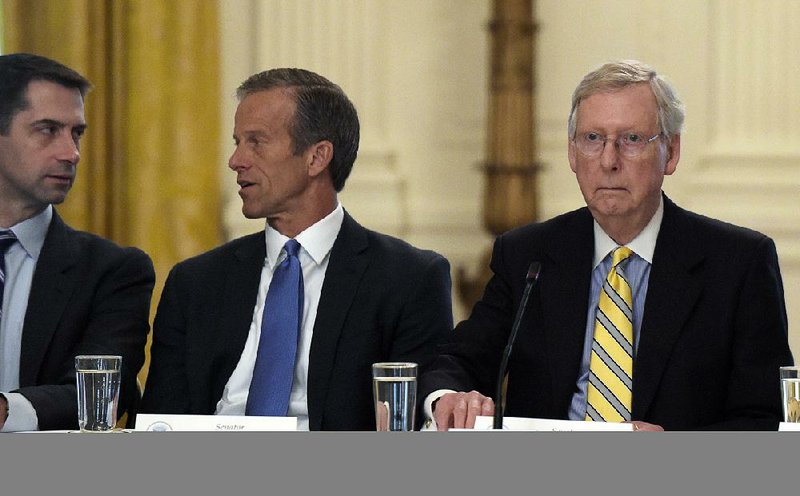 Senate Majority Leader Mitch McConnell of Ky., right, seated next to Sen. Tom Cotton, R-Ark., left, and Sen. John Thune, R-S.D., center, waits for President Donald Trump to join a meeting of Republican senators on health care in the East Room of at the White House in Washington, Tuesday, June 27, 2017. 
