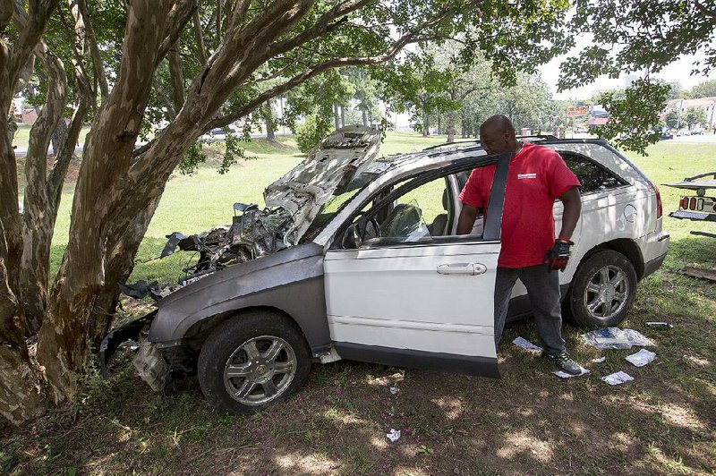 Routh Wrecker Service worker Tony Travis prepares to remove a vehicle from the grounds of the Arkansas School for the Deaf in Little Rock after a fatal crash there Wednesday. 