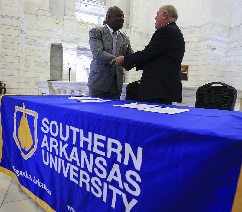 Carlos Ponciano (left), head of the University of Artemisa, and Trey Berry, president of Southern Arkansas University, seal the signing of the schools’ cooperation agreement with a handshake Wednesday at the Capitol.