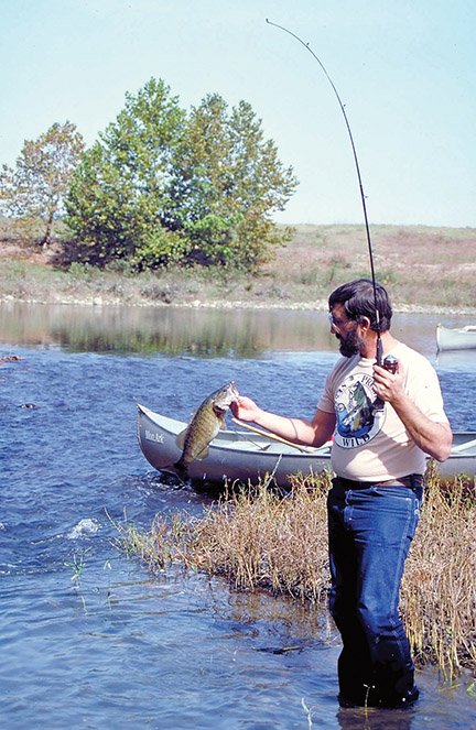 Jim Spencer of Calico Rock lands a nice smallmouth bass on a float trip on the Ouachita River. Canoes provide the ideal means for fishing many of Arkansas’ small mountain streams.