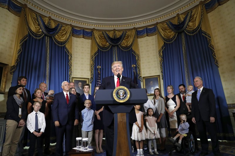 In this July 24, 2017, file photo, President Donald Trump, accompanied by Vice President Mike Pence, Health and Human Services Secretary Tom Price, and others, speaks about healthcare, in the Blue Room of the White House in Washington.