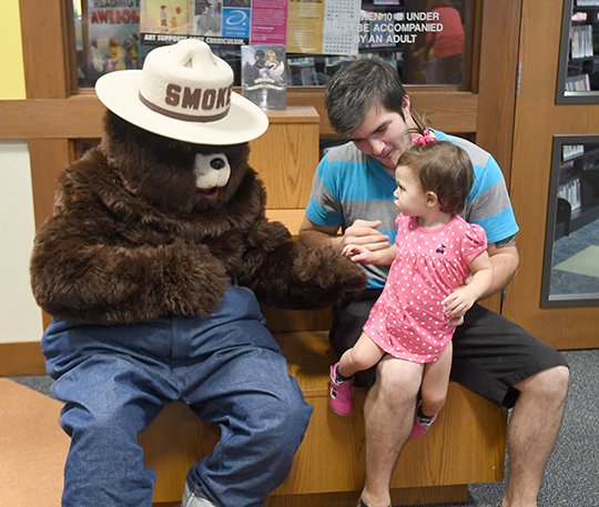 The Sentinel-Record/Mara Kuhn SMOKEY IN STYLE: Lacie Marie Conrad, front, and her father, Shaun Shirley, celebrated Smokey Bear's birthday Wednesday at the Garland County Library. The fire prevention icon turned 73 this week.