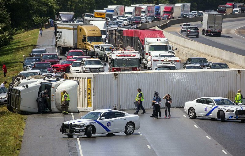 Arkansas Democrat-Gazette/BENJAMIN KRAIN --8/11/17-- 
Police and rescue workers tend to an overturned 18-wheeler on I-40 blocking all lanes of eastbound traffic near the Morgan Maumelle exit Friday afternoon. At least 7 other vehicles crashed behind the truck trying to avoid hitting it after it toppled over. Surprisingly there were no injuries.
