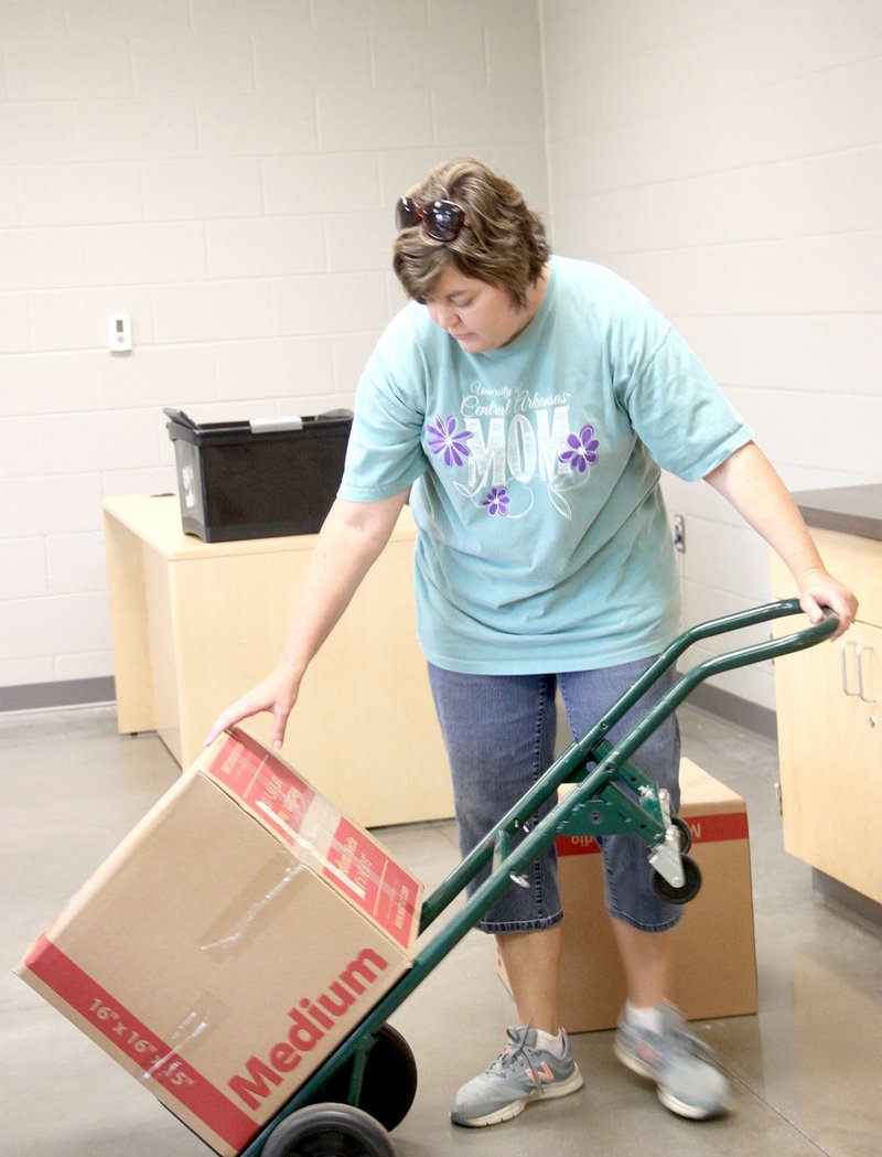 Belyn Rodgers, who teaches oral communications and AP Language and Composition, moves in boxes of books to her new classroom at Farmington High School.