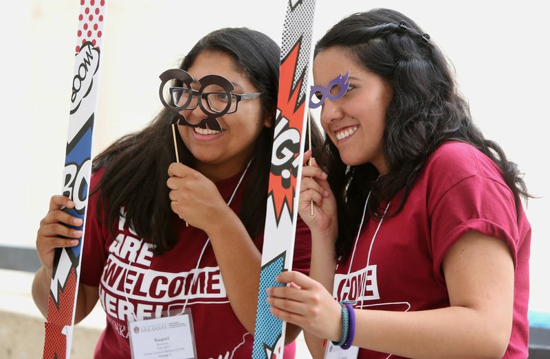 NWA Democrat-Gazette/DAVID GOTTSCHALK Raquel Romero (left), a senior at the University of Arkansas, and Maria Arandia, a sophomore, pose with glasses and a frame Friday as they are photographed on the north terrace of the Union Courtyard on the campus in Fayetteville. The summer-themed photo booth was sponsored by University Programs and included light snacks.