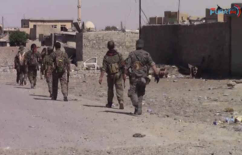 This frame grab from video released Friday, Aug. 11, 2017, and provided by Furat FM, a Syrian Kurdish activist-run media group, shows U.S.-backed Syrian Democratic Forces (SDF) fighters advance in Raqqa, Syria. U.S.-backed Syrian fighters advancing from eastern and western parts of the northern city of Raqqa have linked up for the first time in weeks after launching their offensive against Islamic State group fighters there. (Furat FM, via AP)