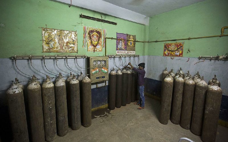 A hospital staff member checks newly arrived oxygen cylinders Saturday at Baba Raghav Das Medical College Hospital in Gorakhpur, India. 