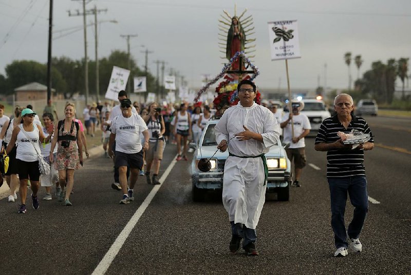 Altar server Anthoney Saenz (second from right) waves incense Saturday as he helps lead a procession toward the Rio Grande to oppose the wall the U.S. wants to build at the Mexican border. 