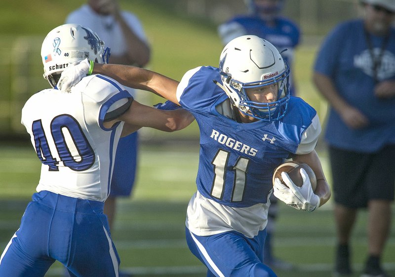 Rogers High junior Will Sims (11) breaks away from sophomore teammate Vincent Vo on Friday during practice at Whitey Smith Stadium in Rogers.