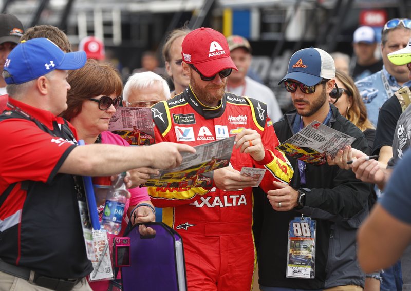Dale Earnhardt Jr. signs autographs in the garage before practice for the NASCAR Cup Series auto race in Brooklyn, Mich., Saturday, Aug. 12, 2017. 