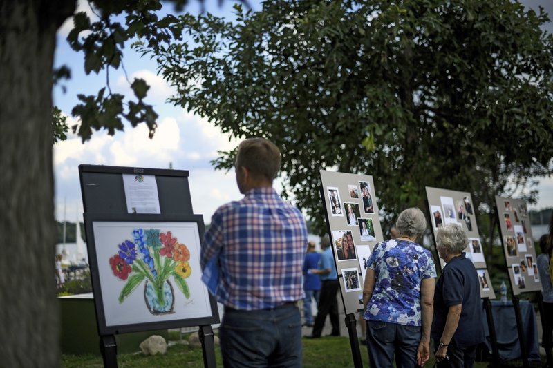 Photos of Justine Damond and artwork inspired by her are displayed during her memorial service Friday, Aug. 11, 2017, at Lake Harriet in Minneapolis. Damond was killed by a Minneapolis police officer on July 15 after she called 911 to report a possible sexual assault near her home. (Aaron Lavinsky/Star Tribune via AP)