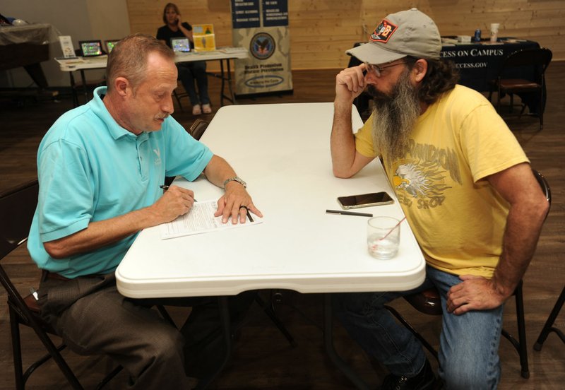 NWA Democrat-Gazette/ANDY SHUPE John Hutchison (right) of Fayetteville, a Marine Corps veteran, speaks Saturday with Jay Mergenschroer, public affairs officer with the U.S. Department of Veterans Affairs’ Little Rock office, while taking part in a information fair during the third annual beneÿt for veterans at the Shelton Tucker Craft American Legion Post 27 in Fayetteville. The event featured music and food and serves as a fundraiser for local veterans.
