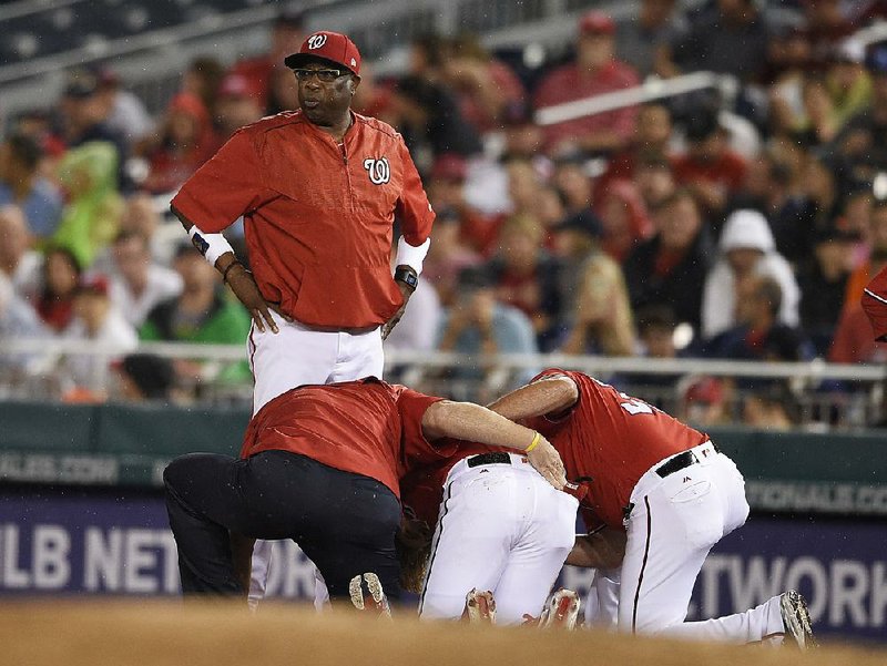 Washington Manager Dusty Baker looks on as outfi elder Bryce Harper receives attention after injuring his knee Saturday night. The injury, diagnosed as a bone bruise, happened at first base.