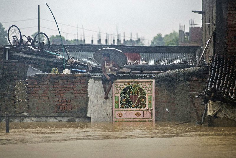 A Nepalese man sits on the wall of his house Sunday in the flooded city of Birgunj.