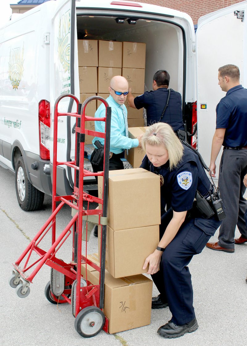 DeAndra Strickland, school resource officer with the Siloam Springs Police Department, and several of her fellow officers unload food boxes Aug. 2 from a Northwest Arkansas Food Bank van. The boxes will be used by officers to assist families in need. Siloam Springs is the sixth law enforcement agency to join in the Food Bank's program, which is sponsored by Woodland Research.