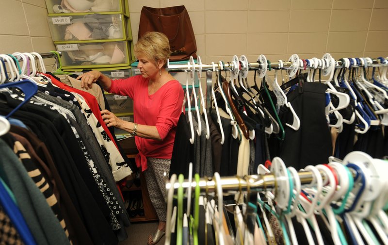 Gwen Shankle of Johnson, a volunteer image consultant with Dress for Success Northwest Arkansas, sorts through clothing Thursday at the agency’s Springdale location.