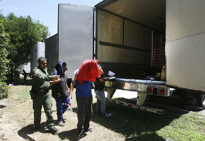 Border Patrol officers escort migrants to a van after they were found Sunday inside a tractor-trailer in Edinburg, Texas.