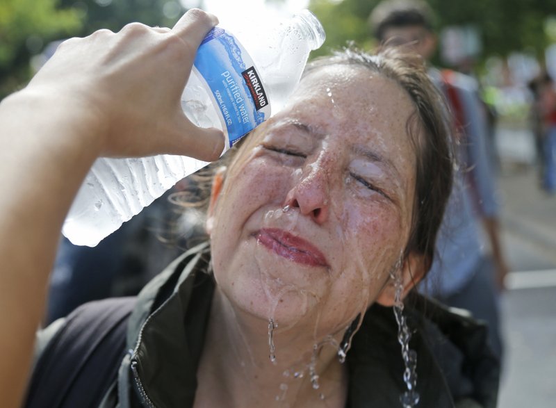 A counter demonstrator gets a splash of water after being hit by pepper spray at the entrance to Lee Park in Charlottesville, Va., Saturday, Aug. 12, 2017. Gov. Terry McAuliffe declared a state of emergency and police dressed in riot gear ordered people to disperse after chaotic violent clashes between white nationalists and counter protestors. 