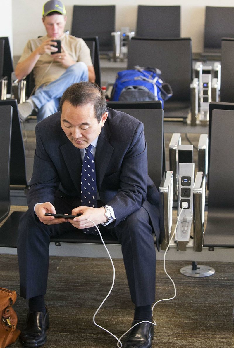 John Park of New York uses a phone charging outlet built into his seat at Bill and Hillary Clinton National Airport/Adams Field in Little Rock while waiting for a flight. 