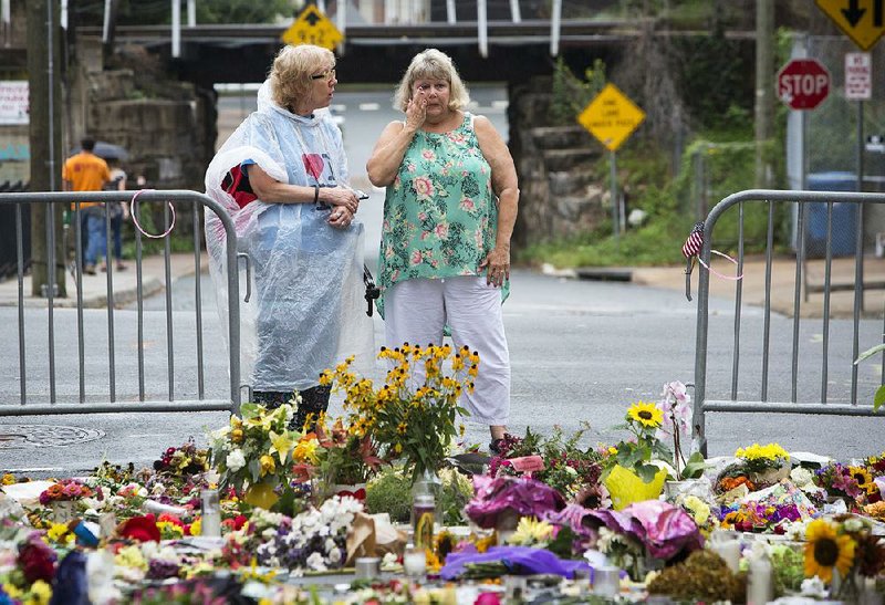 Women visit a memorial at 4th and Water streets on Tuesday in Charlottesville, Va., where Heather Heyer was killed when a car rammed into a group of counterprotesters Saturday. 