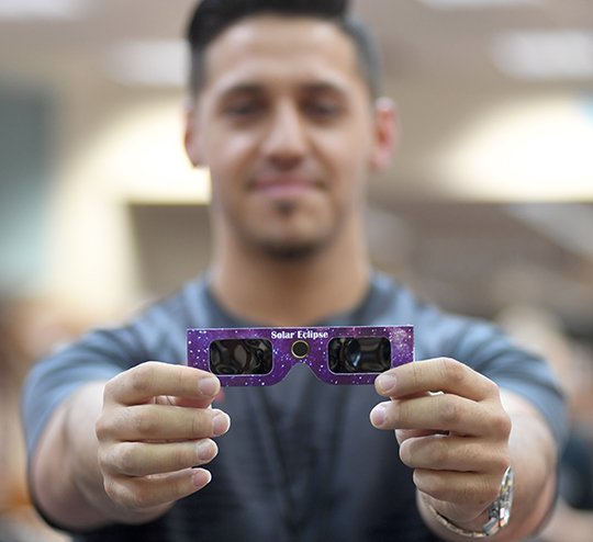 The Sentinel-Record/Mara Kuhn GLASSES RECALLED: Jacob Flores, an employee at the Garland County Library, on Tuesday displays a pair of the library-issued glasses that patrons are being urged not to use when viewing the partial solar eclipse on Monday.