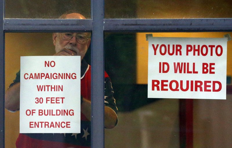 Jim Johnson hangs a sign Tuesday as he prepares the facility for voters in Homewood, Ala.