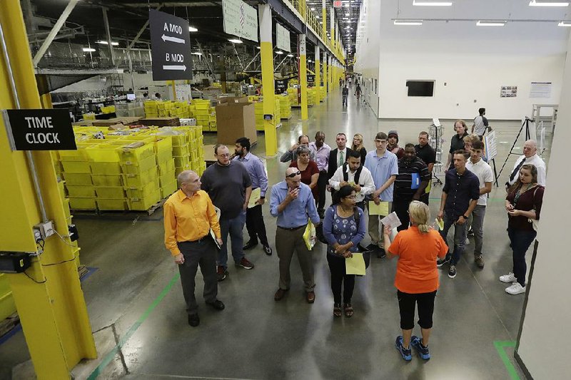 An Amazon employee (bottom right) gives visitors a tour of an Amazon warehouse in Robbinsville Township, N.J., on Aug. 2, the day  Amazon hosted a nationwide job fair.