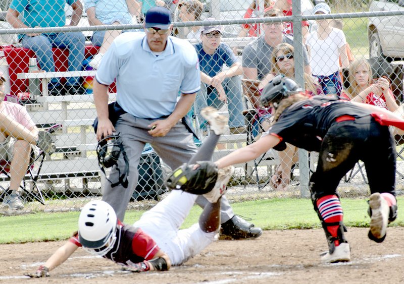 Photo by Rick Peck A Nevada runner slides under the tag of McDonald County catcher Kylie Helm to score the Lady Tigers only run in the Lady Mustangs&#8217; 9-1 win in a four-inning scrimmage held Saturday at MCHS.