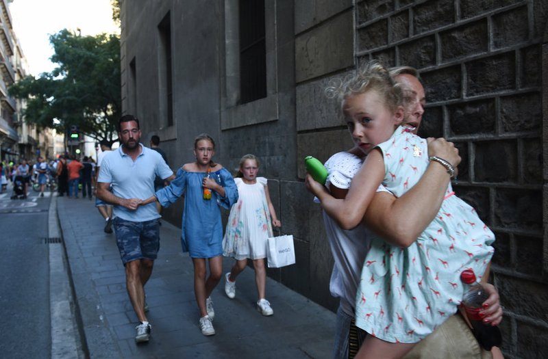 People flee the scene in Barcelona, Spain, on Thursday, Aug. 17, 2017, after a white van jumped the sidewalk in the historic Las Ramblas district, crashing into a summer crowd of residents and tourists and injuring several people, police said. 