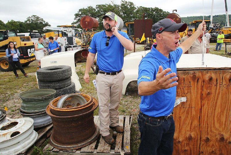 Brad Wooley (left), auctioneer with Block Realty & Auction, and Chris Kimbrell, a ring man with Don Guthery Auctions, auction off Thursday a diesel engine during Washington County’s Road Department surplus auction at the Washington County South Campus in Fayetteville. The county was selling off an assortment of equipment including nine 2011 road graders, bridge trusses and a portable office among other items. The county expected to raise about $500,000.