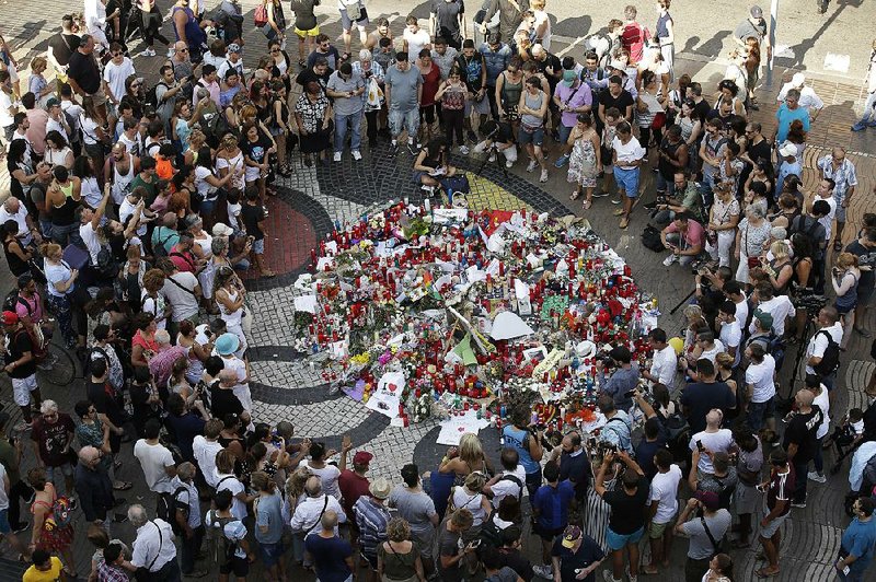 People gather Friday at a memorial tribute on Barcelona’s Las Ramblas promenade for victims of Thursday’s van attack. Flowers, messages and candles were placed on the Joan Miro mosaic in the pavement, the spot where the van stopped.
