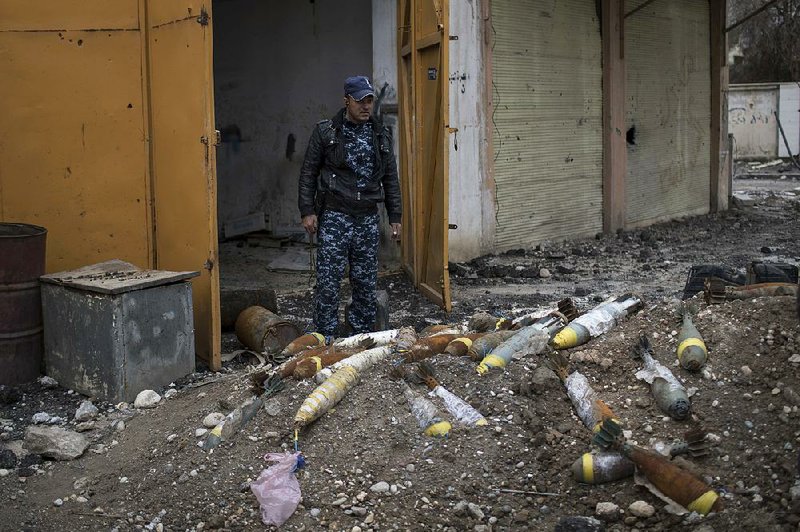 An Iraqi police officer in March stands next to unexploded bombs left in western Mosul by Islamic State militants. Some estimates say it may take 25 years to clear western Mosul of explosives.