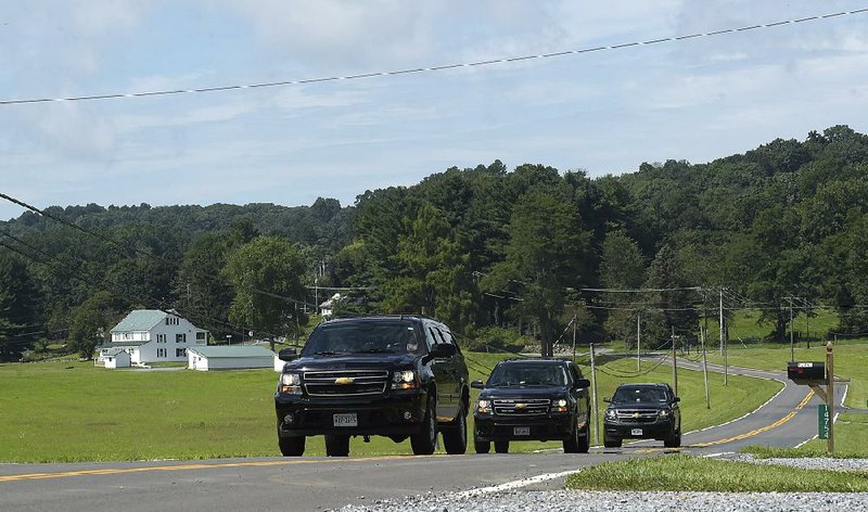 Official vehicles travel a road near Camp David in Maryland, where President Donald Trump met Friday with national security advisers.