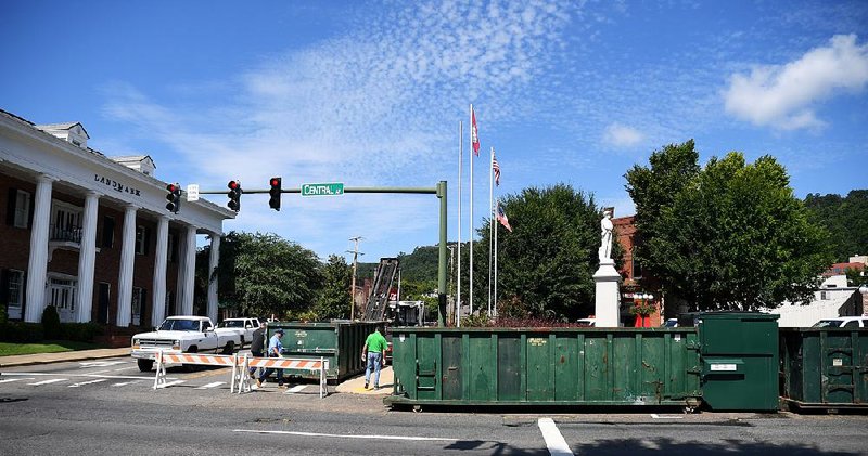 Hot Springs sanitation workers place large trash bins around a Confederate memorial on Friday ahead of a rally today.