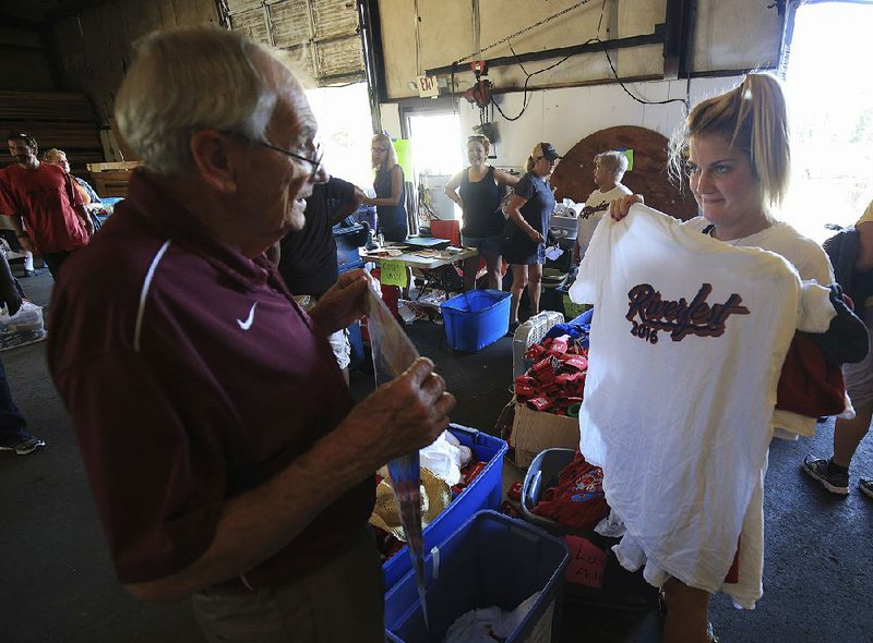 Anna Berkemeyer shows a Riverfest T-shirt to her grandfather Bob Selig as they shop Friday during the Riverfest sale in Little Rock.