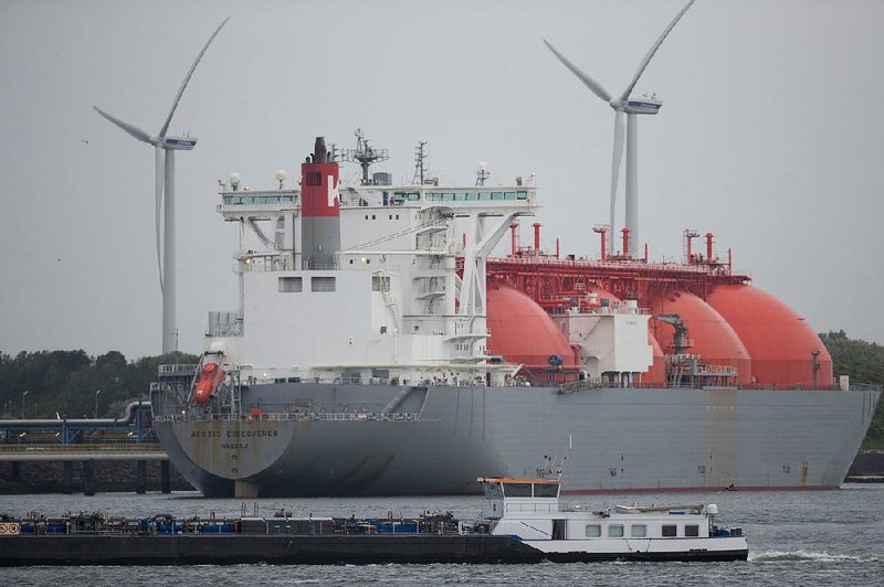 The Arctic Discoverer liquefi ed natural gas (LNG) tanker, operated by K Line LNG Shipping UK Ltd., sits moored at the Gate LNG terminal as wind turbines stand beyond in the Port of Rotterdam in Rotterdam, Netherlands, in June.