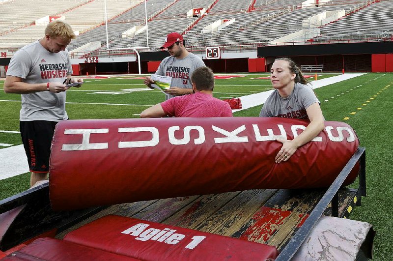 Nebraska student manager Kelli Leachman carries a goal post pad as she and other managers prepare for a Cornhuskers practice.