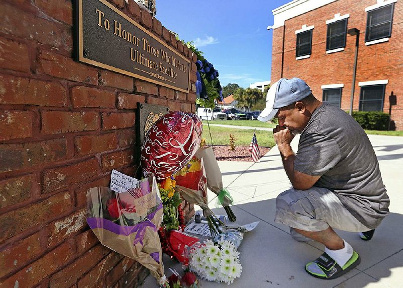 After placing flowers at a makeshift memorial Saturday, Miguel Velez prays for the officer killed in Kissimmee, Fla.
