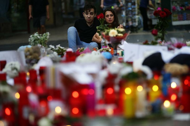 A couple in Barcelona, Spain, look over a memorial of flags, messages and candles Saturday at the scene of Friday’s terrorist attack, when a van driver killed at least 13 people.