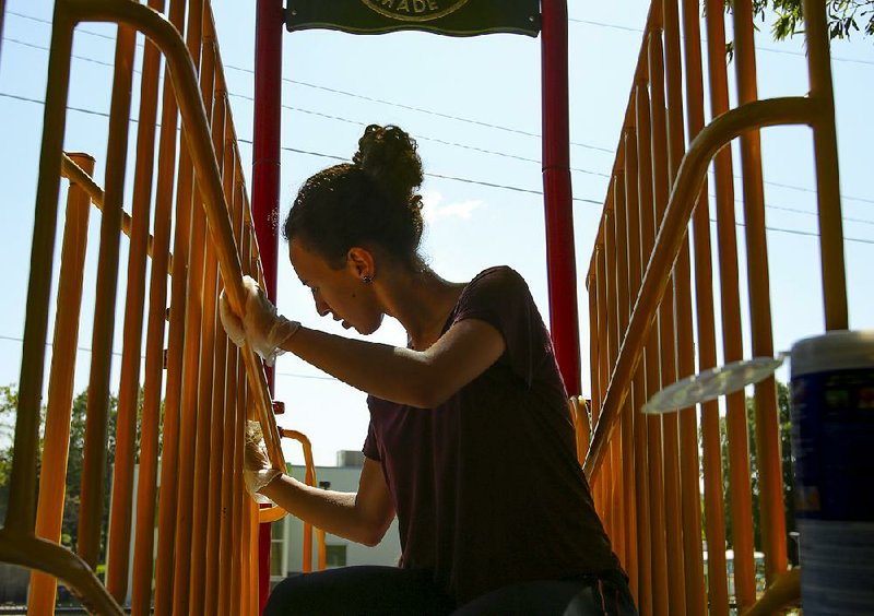 Yaala Muller, a University of Arkansas Clinton School of Public Service student, cleans playground equipment Saturday at Our House in Little Rock during a global day of service on former President Bill Clinton’s 71st birthday.
