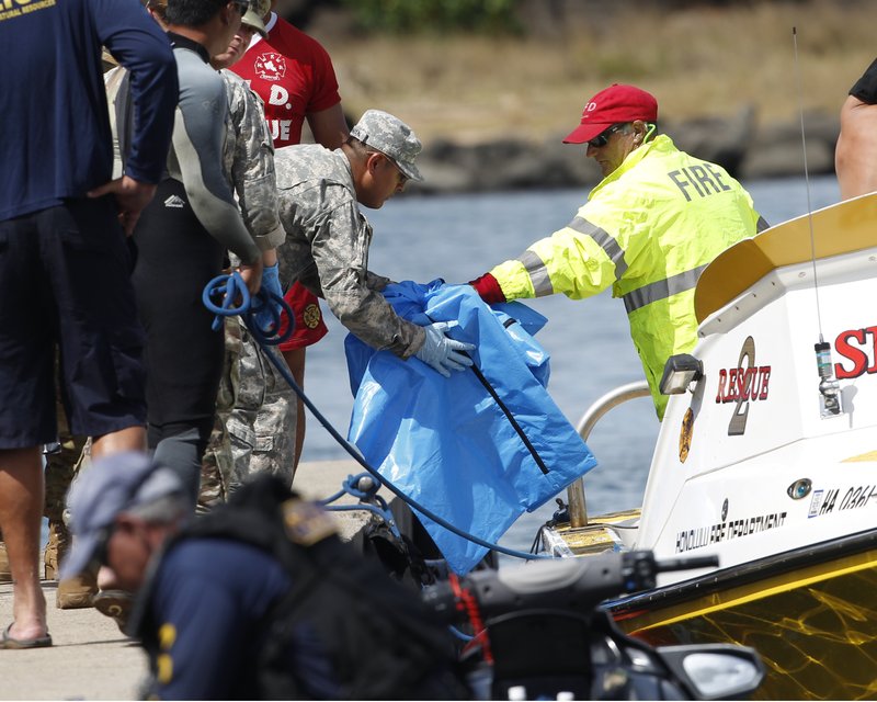 Water safety officials hand over possible debris from an Army UH-60 Black Hawk helicopter crash to military personnel stationed at a command center in a harbor, Wednesday, August 16, 2017 in Haleiwa, HI. An Army helicopter with five on board crashed several miles off Oahu's North Shore late Tuesday. Rescue crews are searching the waters early Wednesday. 