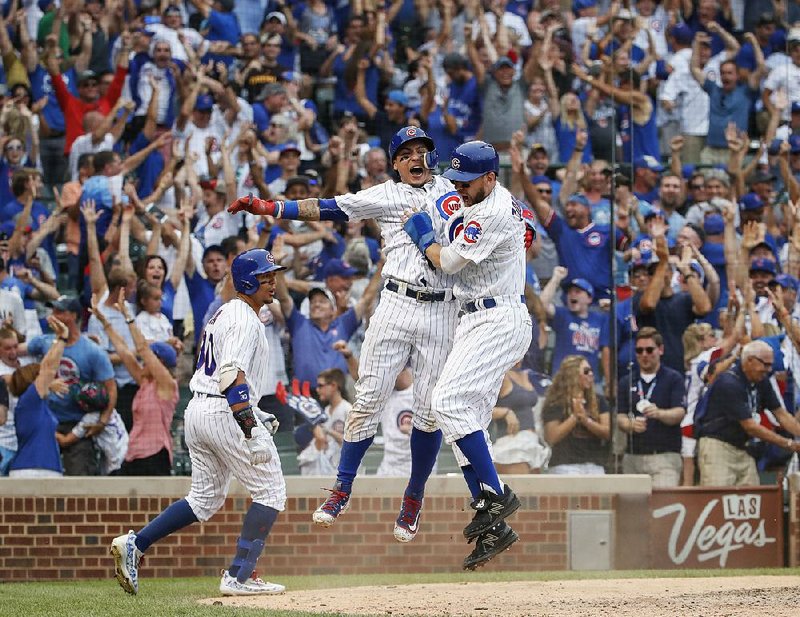 Chicago’s Javy Baez (center) celebrates with Ben Zobrist (right) after scoring on a game-winning two-run single by Alex Avila in the 10th inning of the Cubs’ 6-5 victory over Toronto on Sunday.