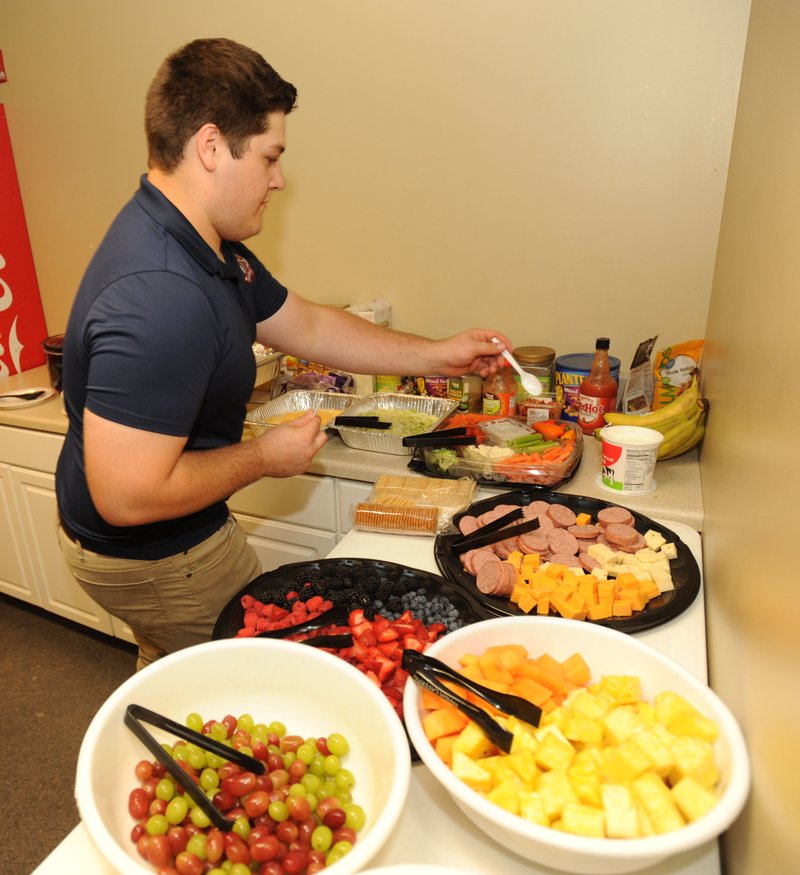 Tyler Burson, a Springdale Har-Ber graduate and current Northwest Arkansas Community College student, arranges food Aug. 9 for the visiting Midland Rockhounds while performing his duties as the clubhouse assistant for the Northwest Arkansas Naturals at Arvest Ballpark in Springdale.