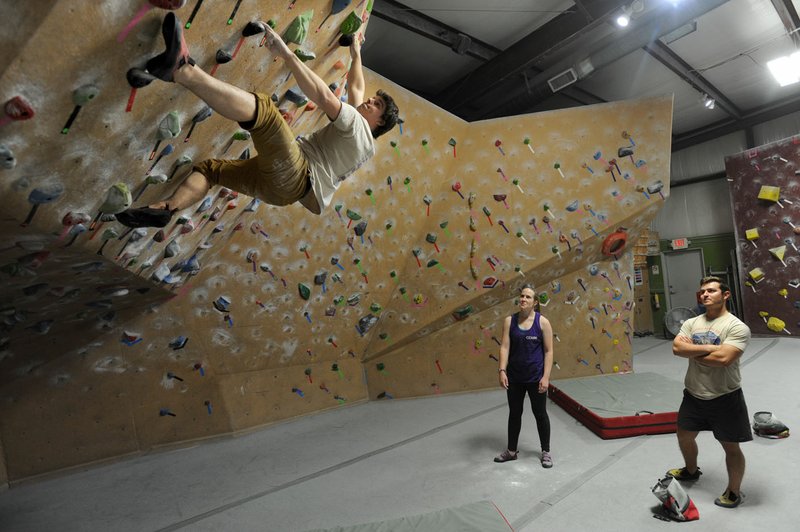 Jason Groves (from left), co-owner of Ozark Climbing Gym in Springdale, climbs Friday on one of the gym’s three climbing walls as his wife, Bridgette Groves, and Landon Carpenter, a worker at the gym, watch. The Bentonville Planning Commission has approved the construction of a similar facility.